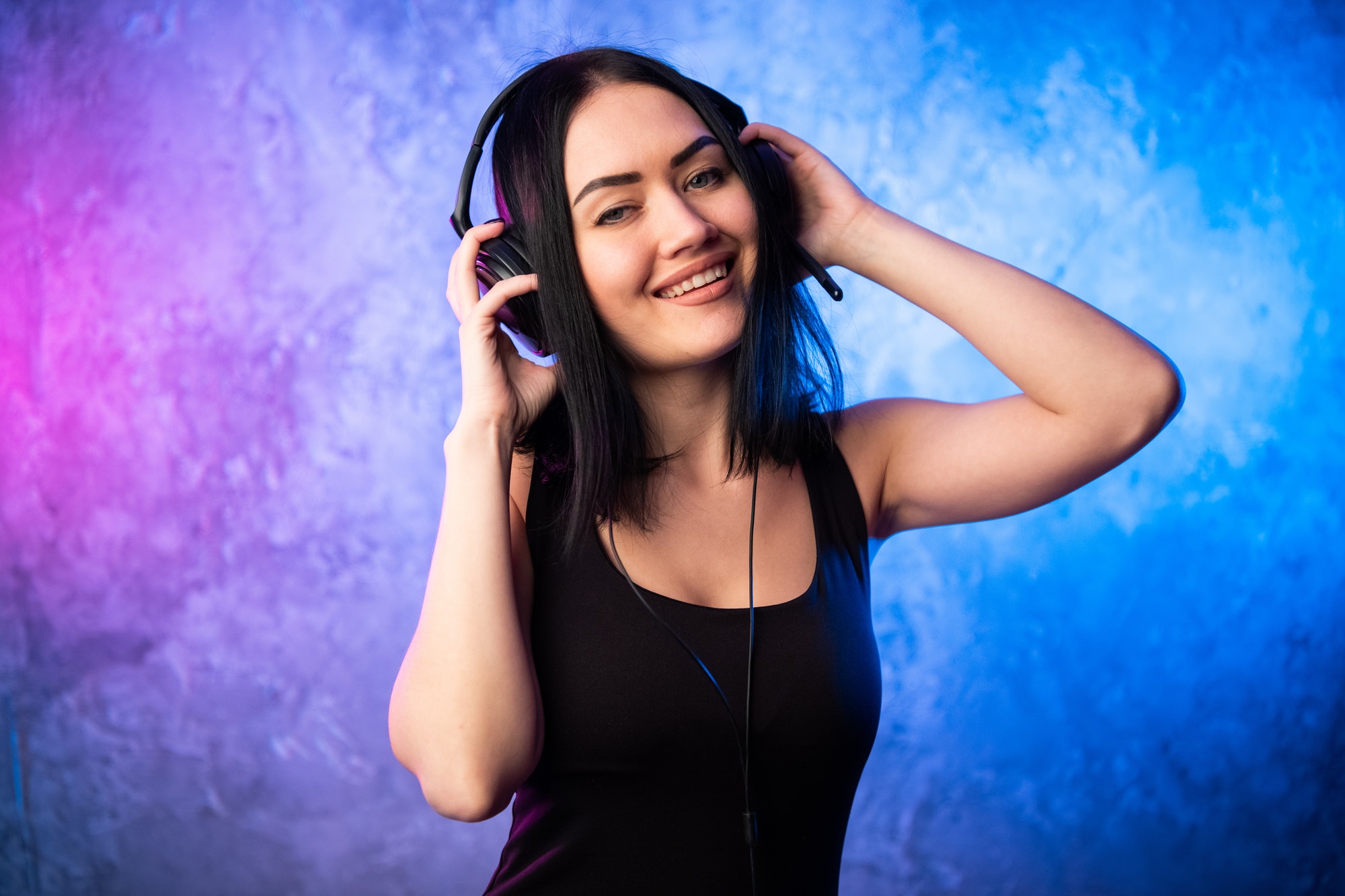 Speak With The Pastor 1 colorful portrait in blue and pink ligth of a young dj woman wearing headset and enjoying an